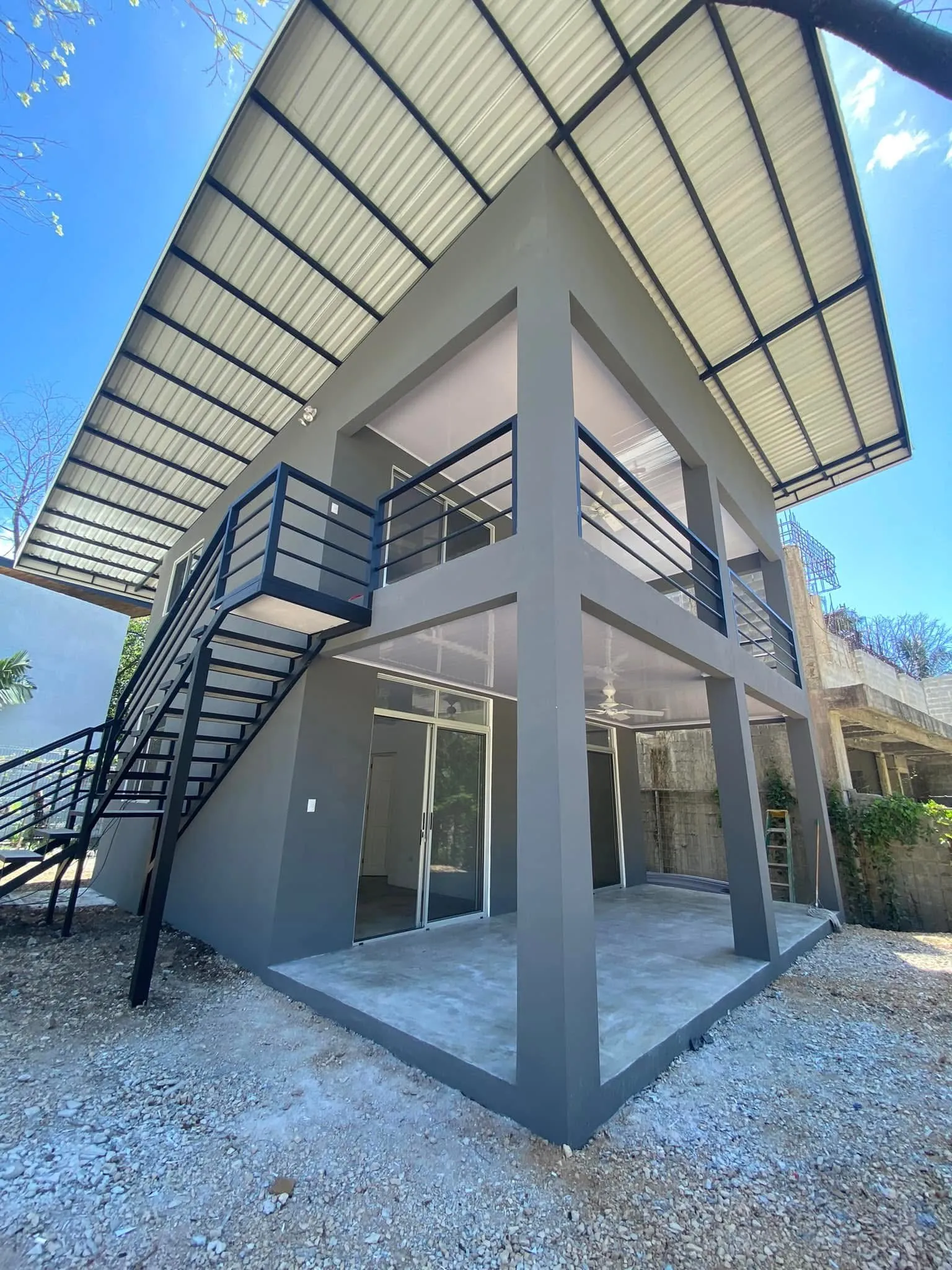 Gray concrete two-story Matta Ruiz construction with exposed steel stairs and standing-seam metal roof in Santa Teresa.