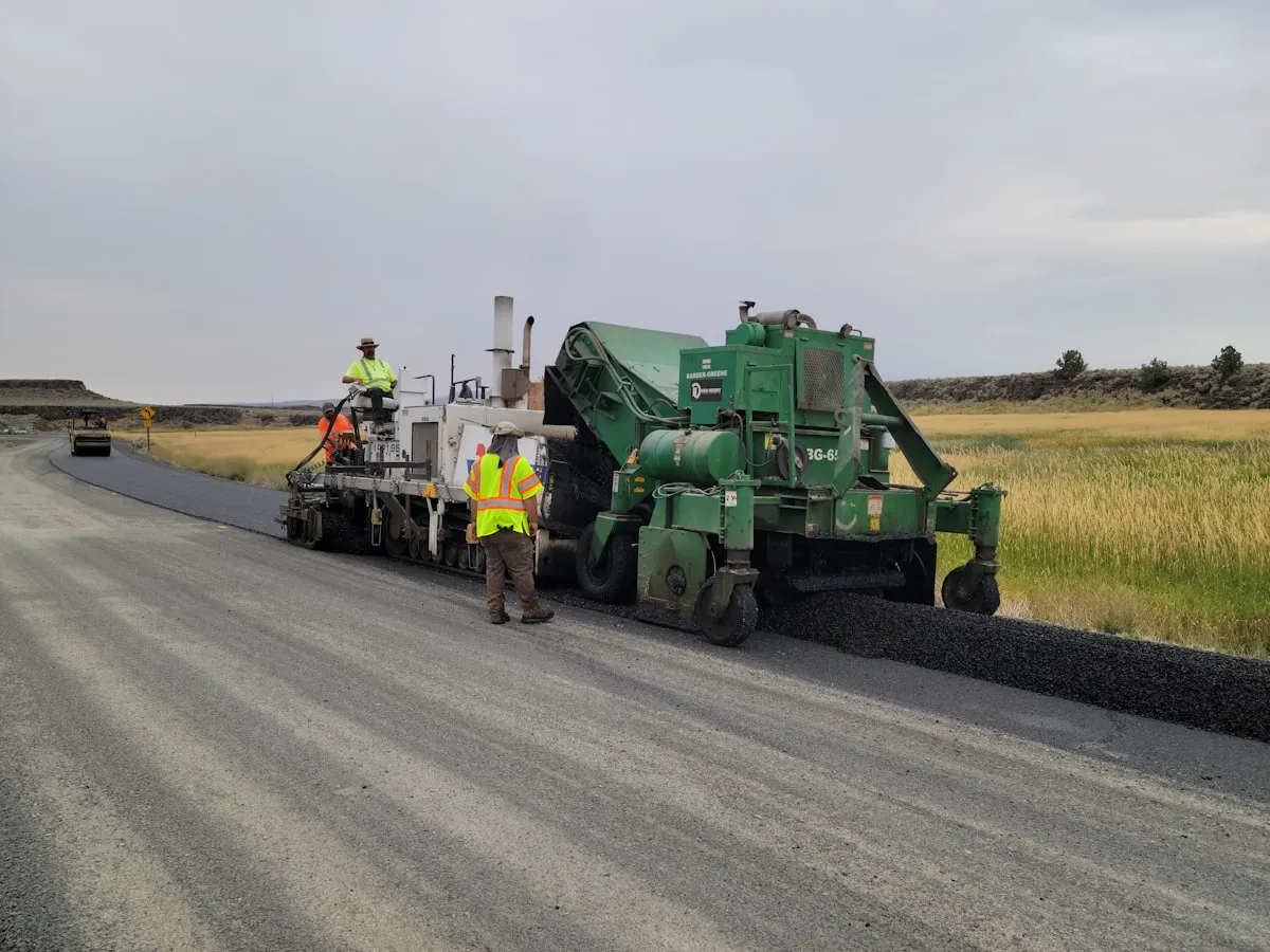Reference image of a paving crew at work — real photos of Matta Ruiz road and access builds coming soon.